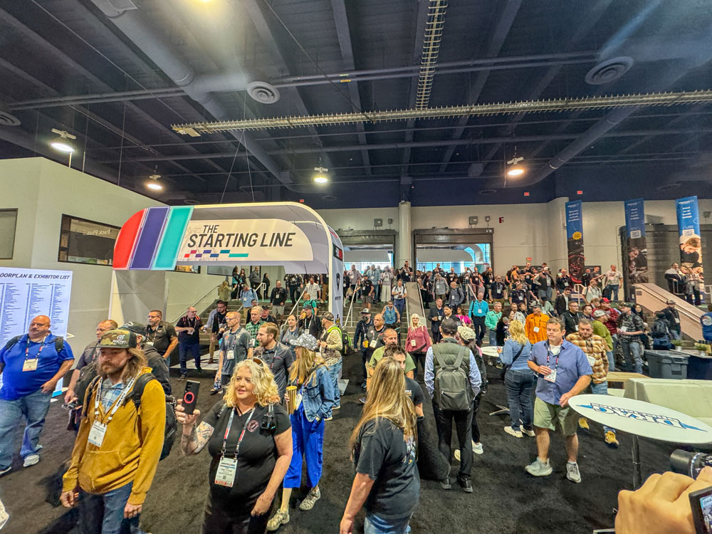 Hero image showing a busy motorcycle expo hall with crowds and bikes on display