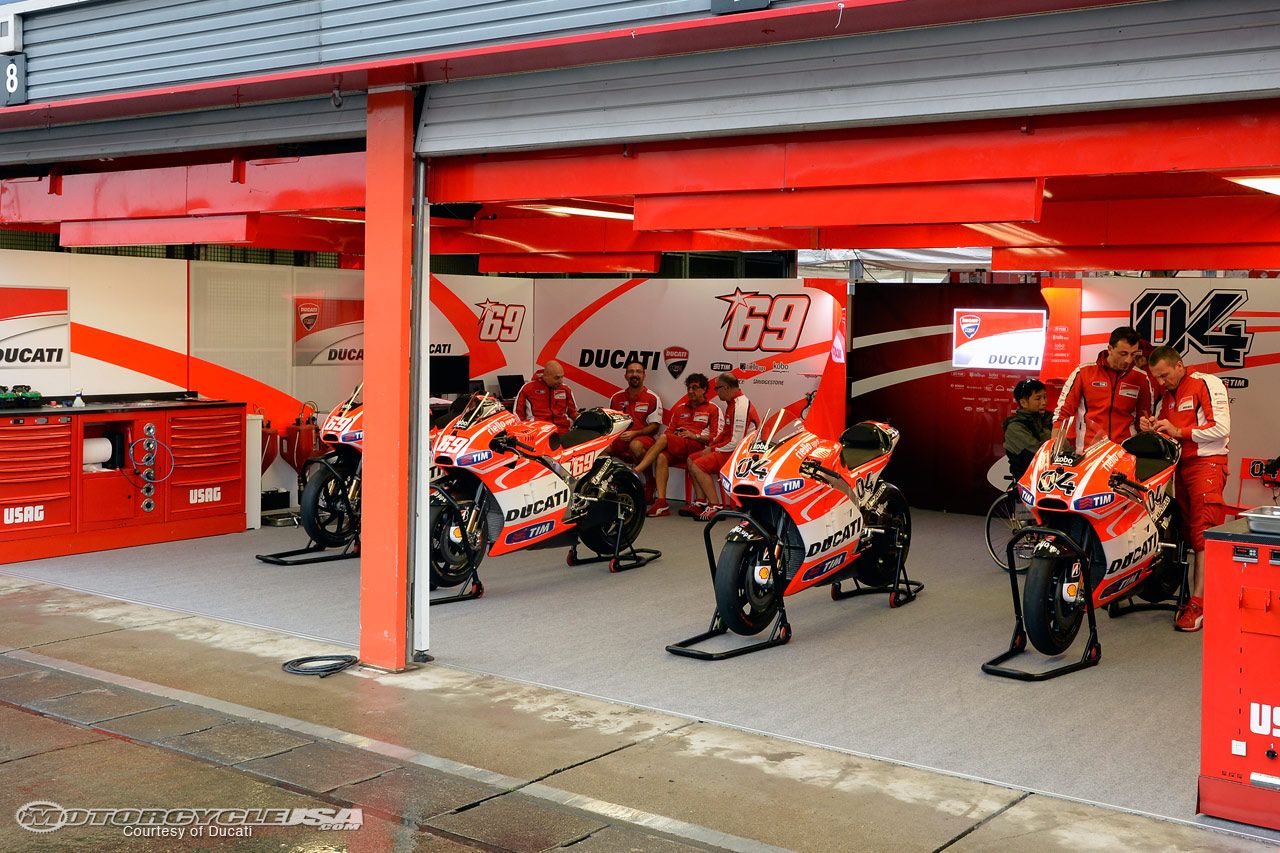 Paddock scene showing team mechanics working on race bikes
