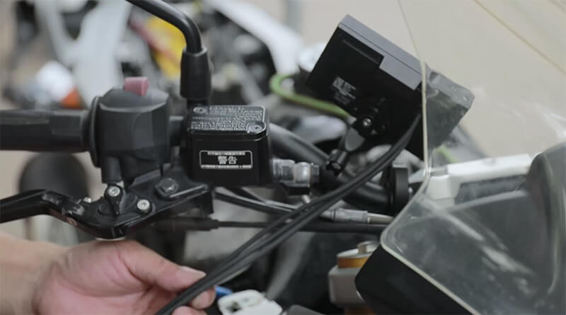 Close-up of dash cam being mounted or wired to a motorcycle