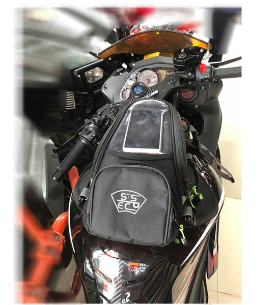 Strap-on tank bag mounted on a sport bike showing strap routing around fairings