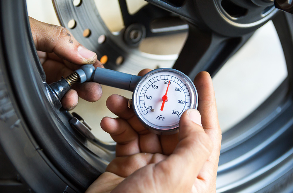 Rider checking tire pressure with gauge for accuracy comparison section