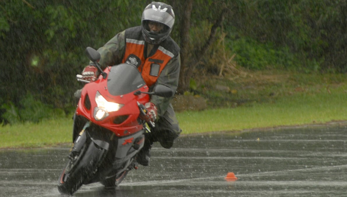 Hero image showing rider in rain gear with focus on gloved hands on handlebars