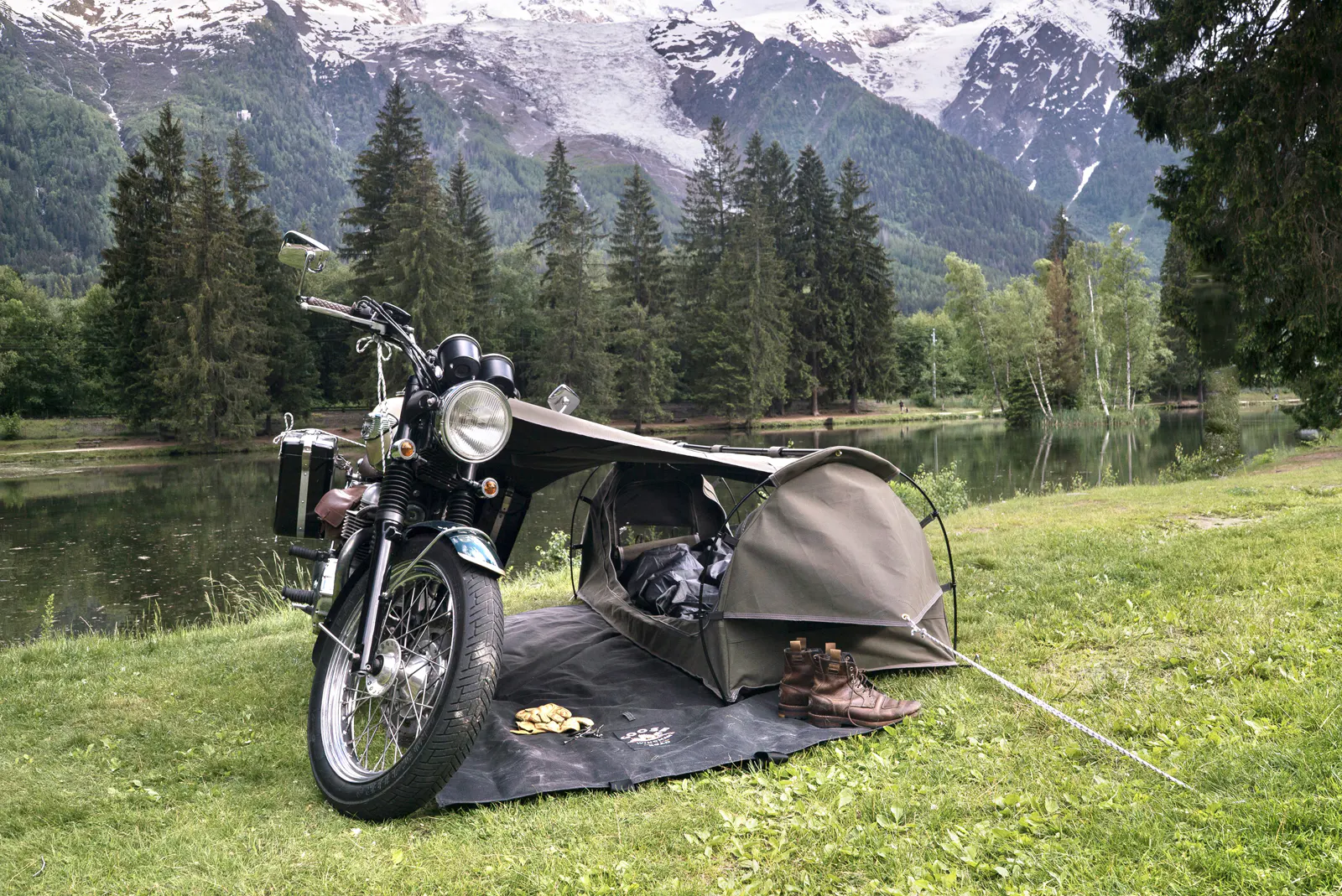 Overlanding campsite with motorcycle parked beside tent in remote wilderness