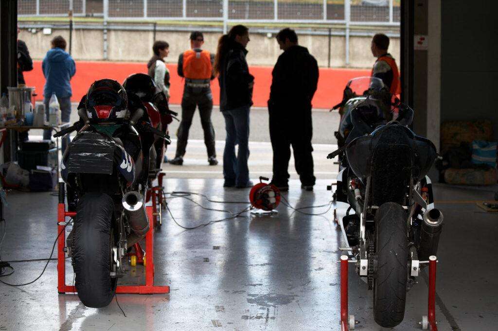 Riders preparing bikes in pit lane before track session