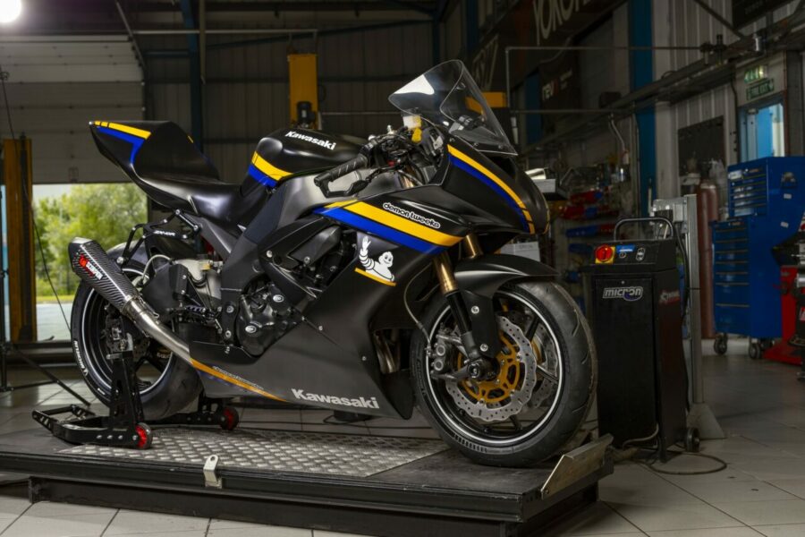 Rider or crew performing pre-track tech inspection on a motorcycle in the paddock