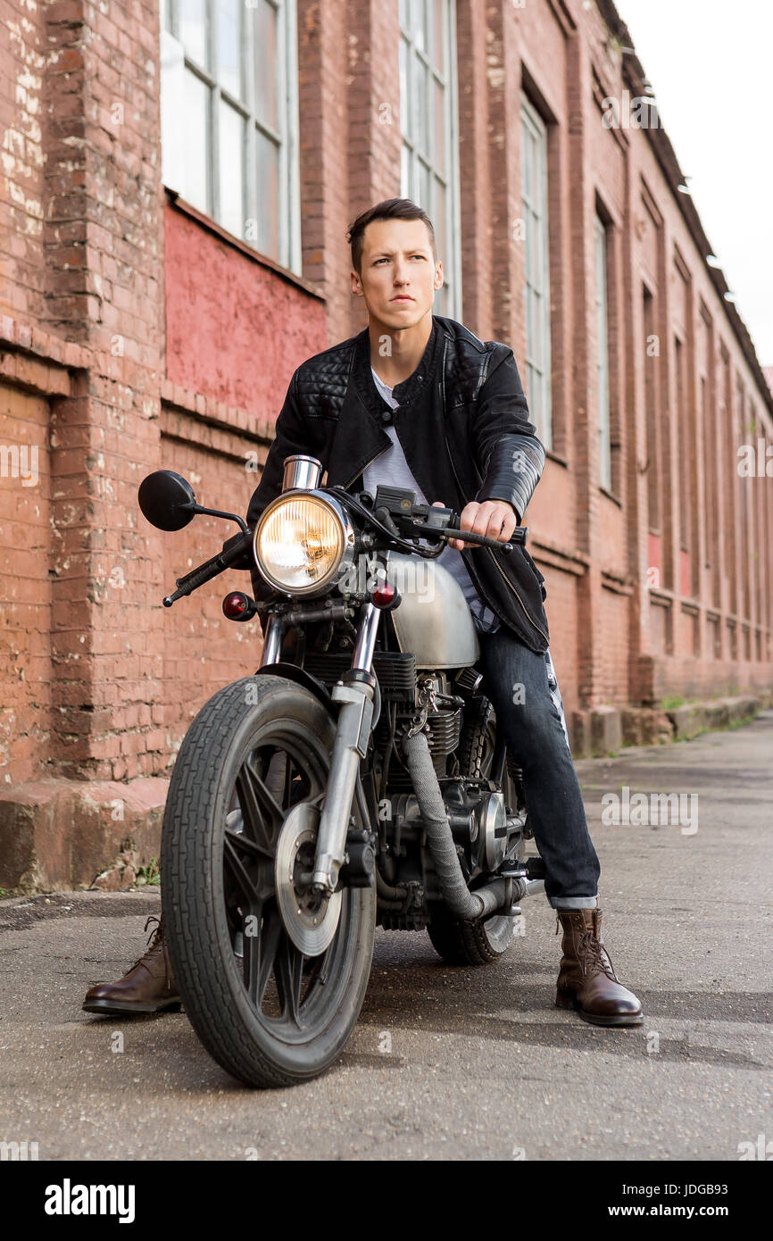 Close-up of a rider in period-appropriate dapper attire on a vintage or neo-retro motorcycle