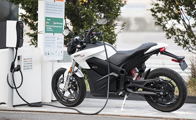 Rider plugging in electric motorcycle at a public charging station