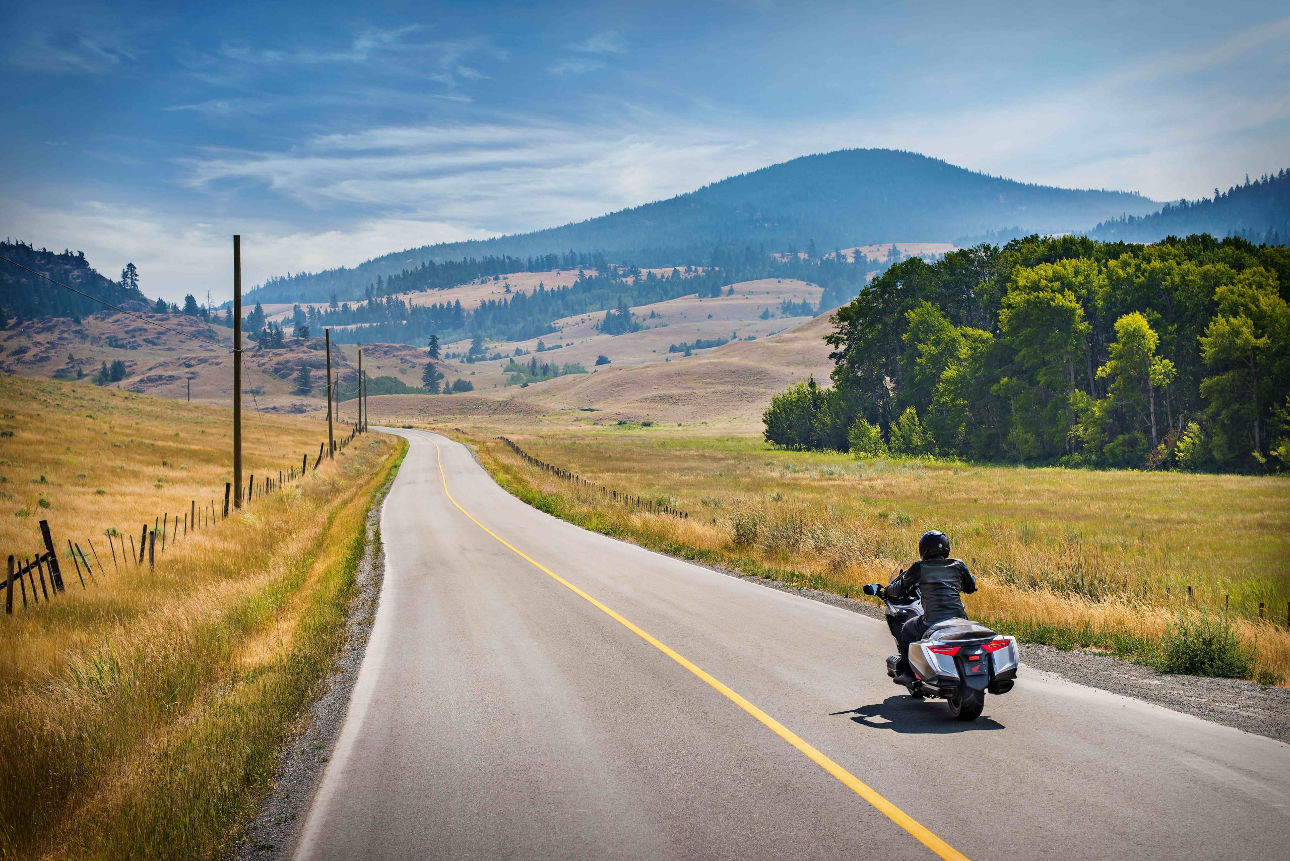 Wide landscape shot of rider on sport tourer on open highway, evoking the cross-country journey