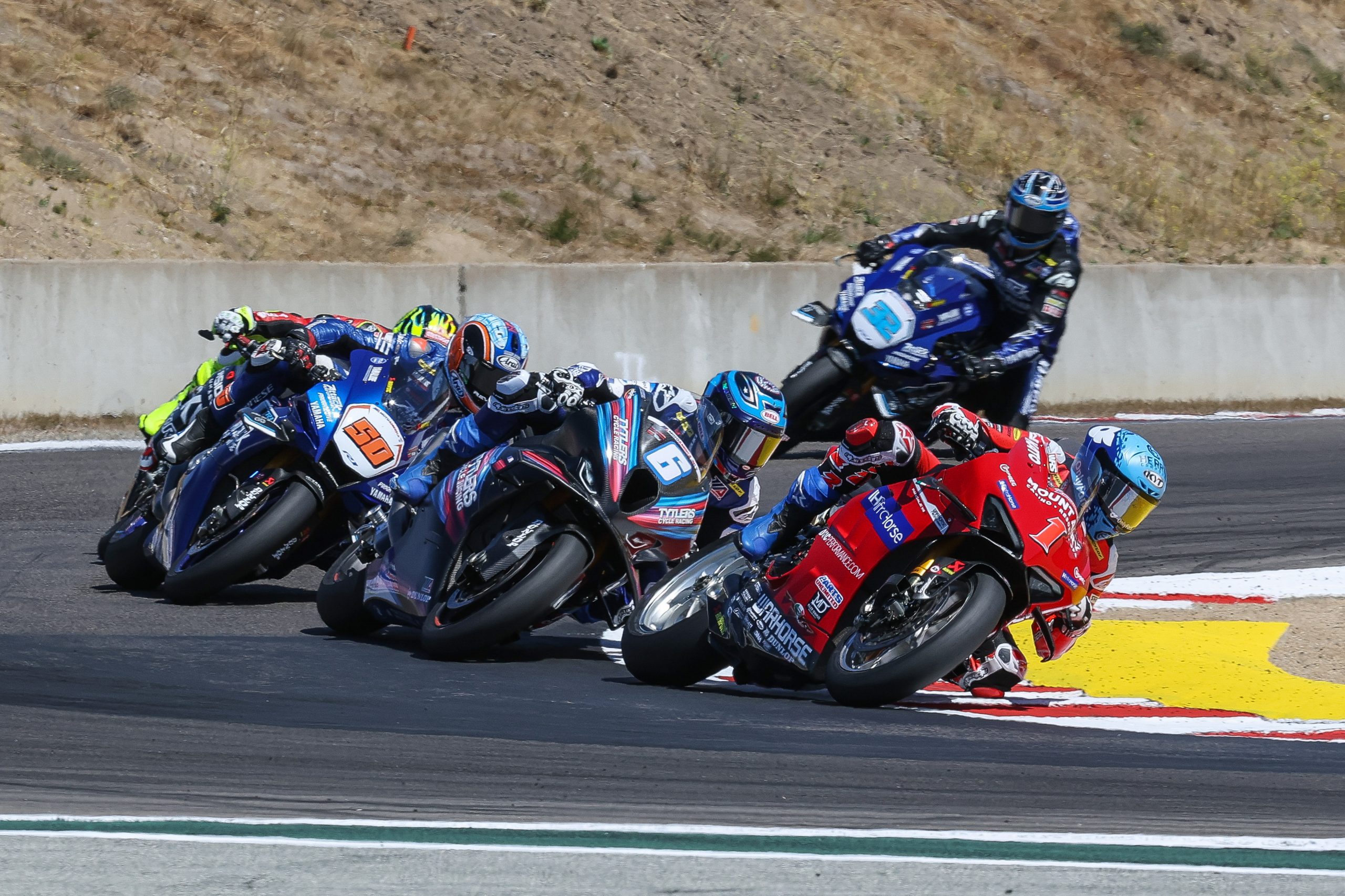 Hero image — dramatic race action at Laguna Seca's Corkscrew