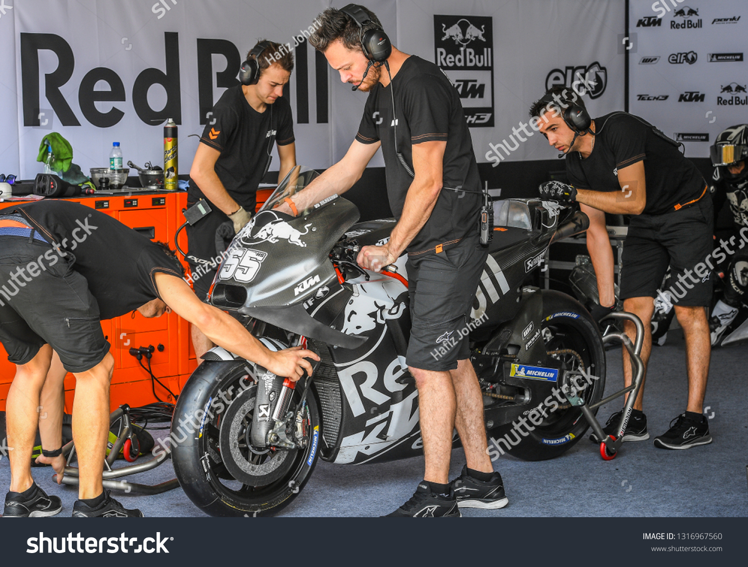 Team paddock scene showing mechanics preparing a MotoGP bike