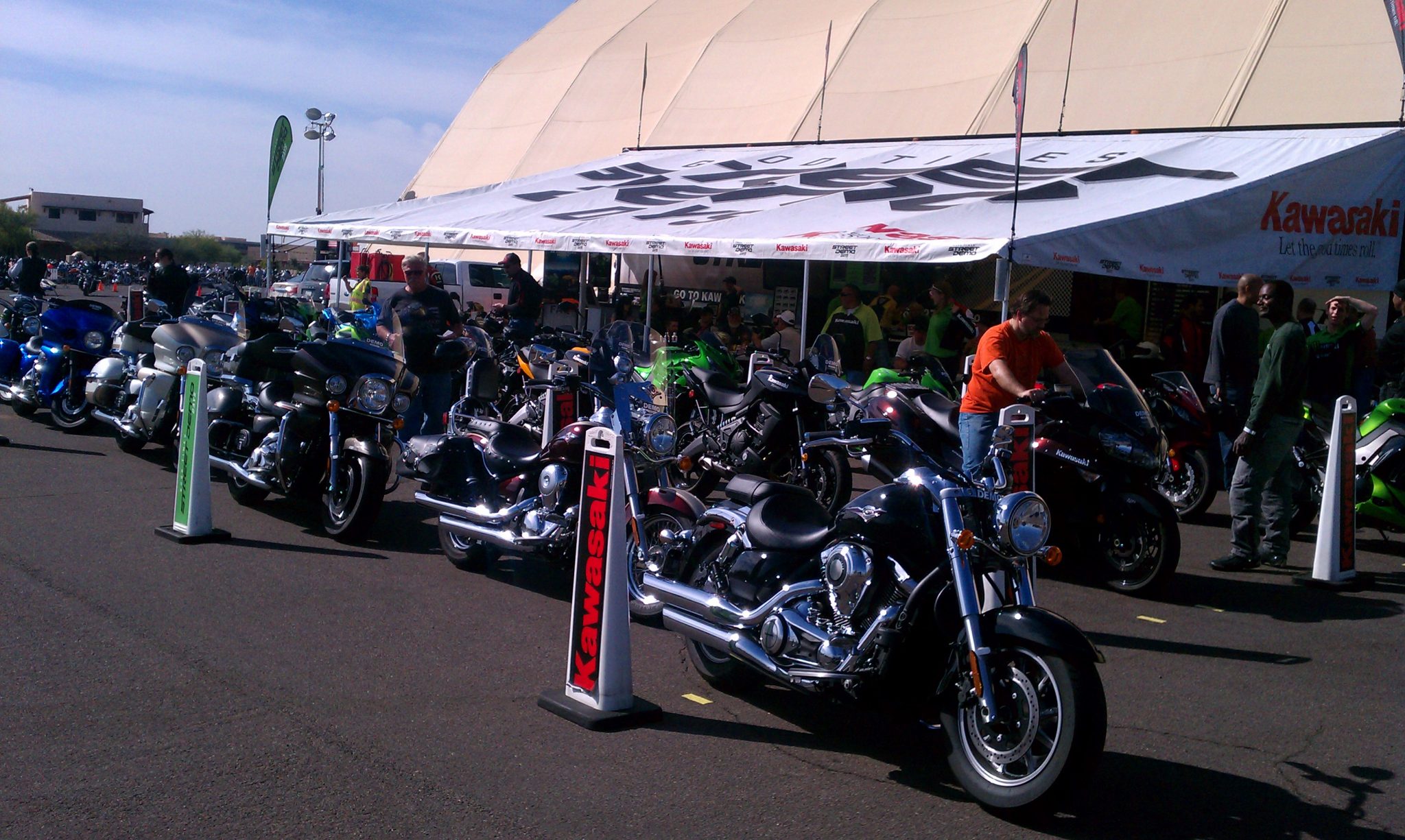 Hero image showing riders at a dealership demo event in a sunny desert setting
