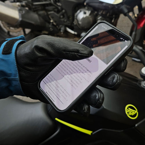 Rider using gloved hand to operate a GPS touchscreen while stopped